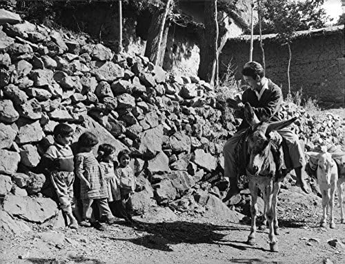 Foto vintage de Jacques Charrier olhando para crianças pequenas, sentado na mula.